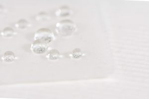 Water droplets repelled by wax coating on white fabric
